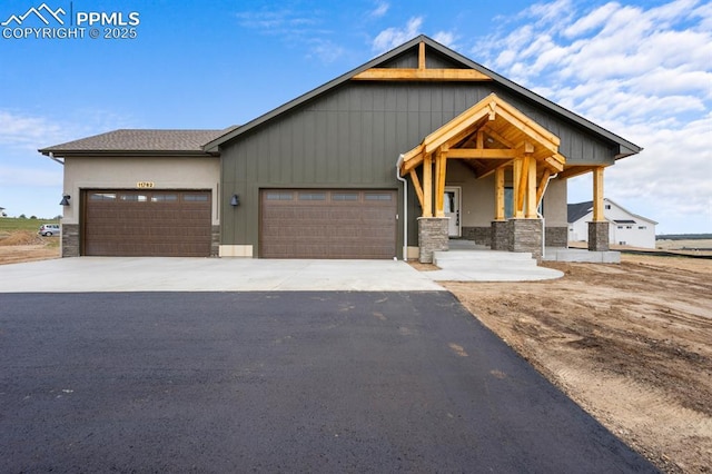 craftsman-style house with stone siding, aphalt driveway, and an attached garage