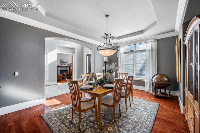 dining room with crown molding, a raised ceiling, and hardwood / wood-style floors