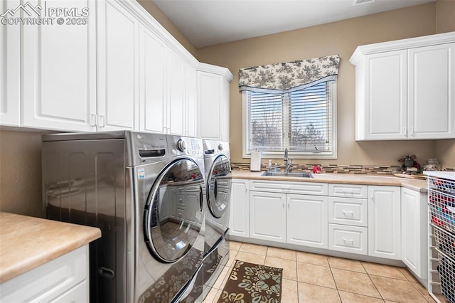 laundry area with cabinets, light tile patterned flooring, sink, and washer and clothes dryer