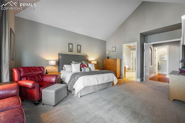 carpeted bedroom featuring ensuite bathroom and high vaulted ceiling