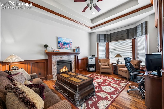 office area featuring a premium fireplace, wood-type flooring, ceiling fan, and a tray ceiling