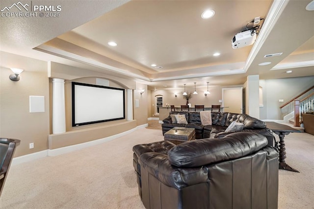 carpeted cinema with a tray ceiling and decorative columns