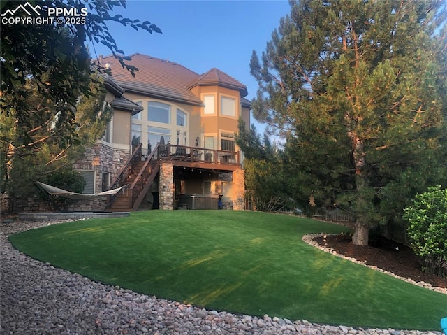 rear view of house with a wooden deck and a lawn