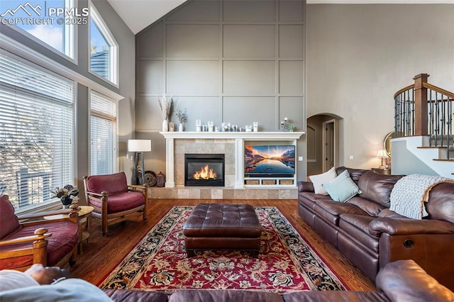 living room with a wealth of natural light, a fireplace, high vaulted ceiling, and wood-type flooring