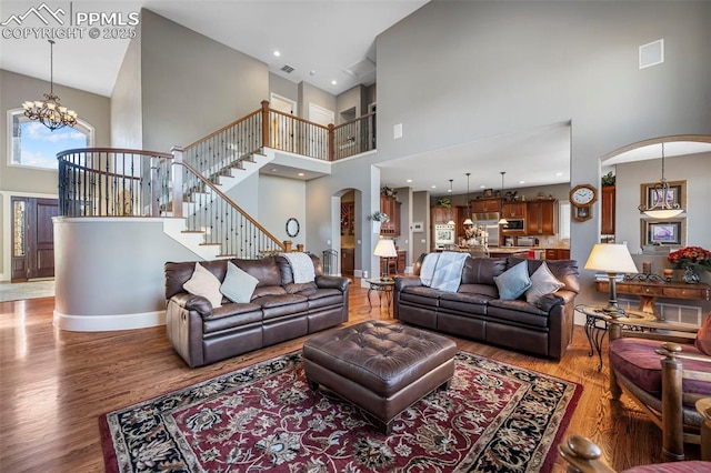 living room featuring an inviting chandelier, a high ceiling, and hardwood / wood-style flooring