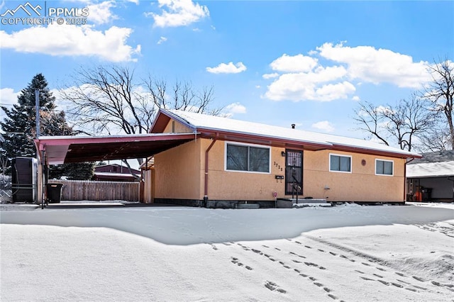 view of front of house featuring a carport, fence, and stucco siding