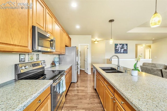 kitchen featuring sink, appliances with stainless steel finishes, hanging light fixtures, and light stone counters