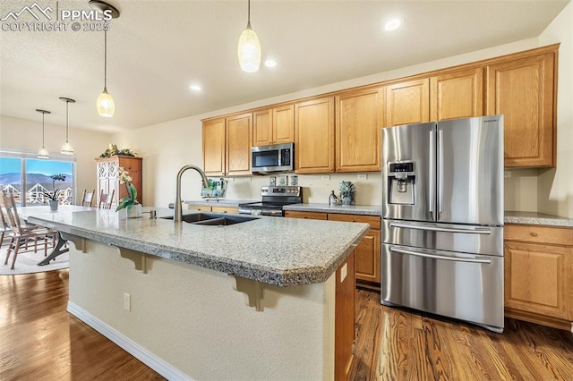 kitchen with sink, stainless steel appliances, a kitchen island with sink, and a breakfast bar area