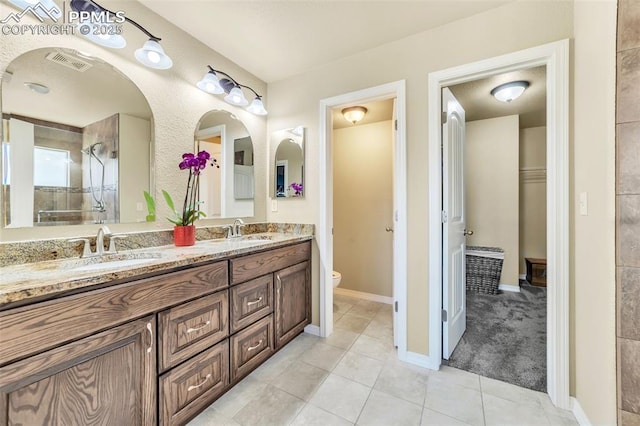 bathroom with vanity, tiled shower, toilet, and tile patterned floors