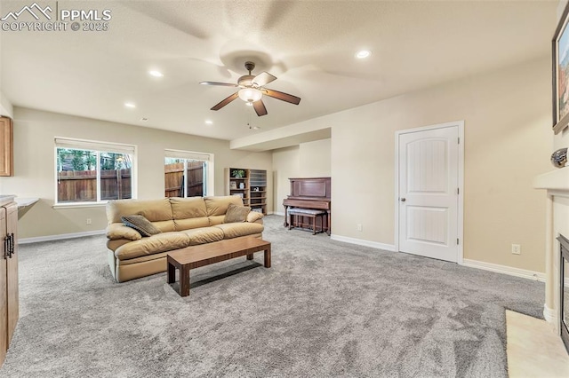 living room featuring light carpet, ceiling fan, and a fireplace