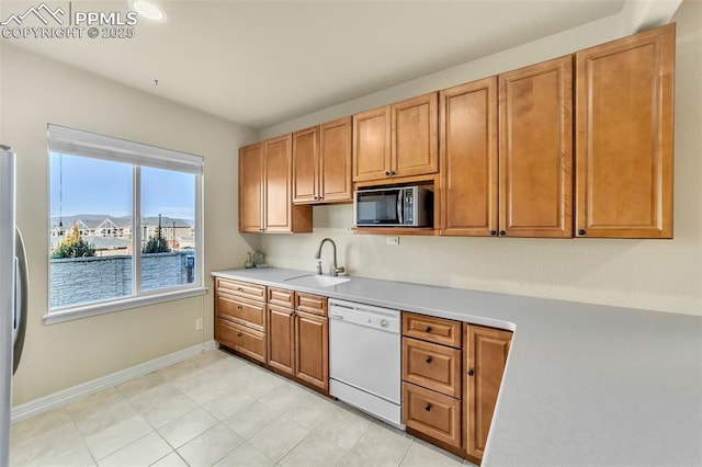 kitchen featuring white dishwasher, stainless steel fridge, and sink