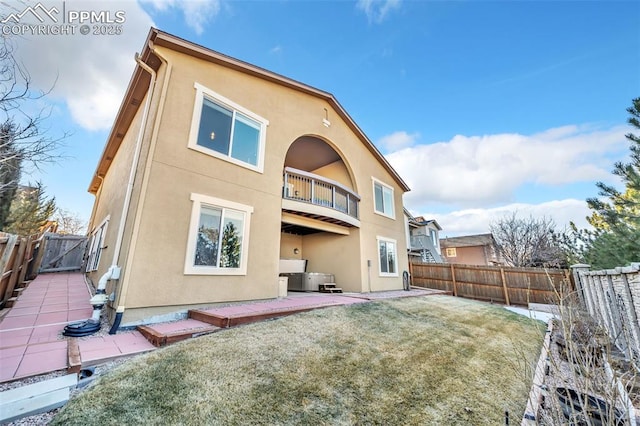 back of property with a yard, a patio area, and a balcony