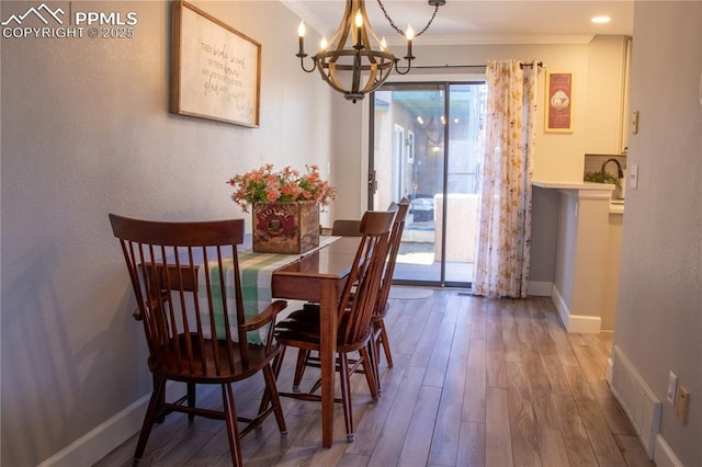 dining room featuring hardwood / wood-style floors, ornamental molding, and a chandelier