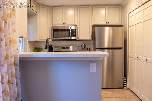 kitchen featuring tasteful backsplash, stainless steel appliances, and light hardwood / wood-style floors