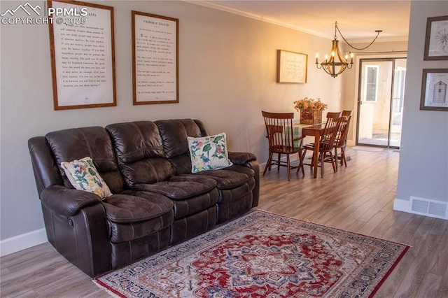 living room featuring hardwood / wood-style flooring, crown molding, and an inviting chandelier