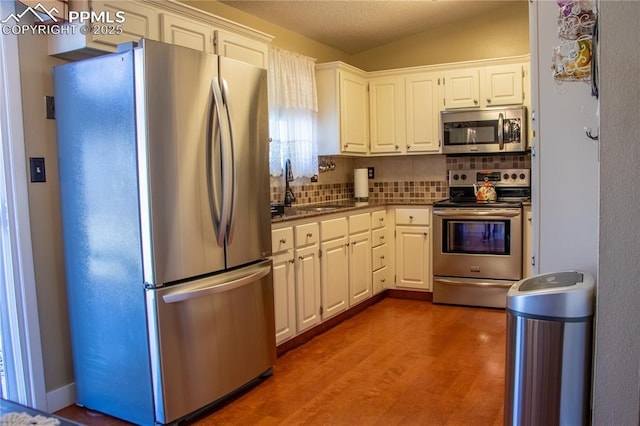 kitchen with dark wood-type flooring, sink, white cabinets, stainless steel appliances, and backsplash