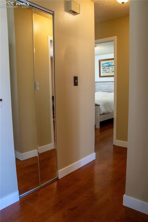 hallway featuring a textured ceiling and dark hardwood / wood-style flooring