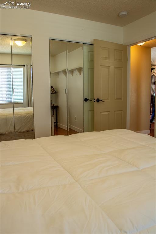 unfurnished bedroom featuring a textured ceiling and multiple closets