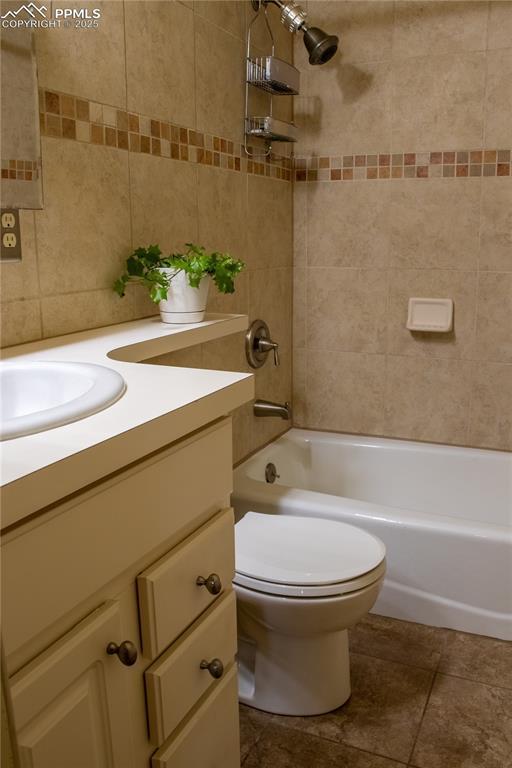 full bathroom featuring vanity, tiled shower / bath, tile patterned floors, and toilet