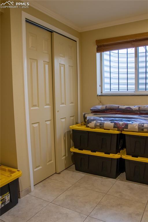 tiled bedroom with ornamental molding and a closet