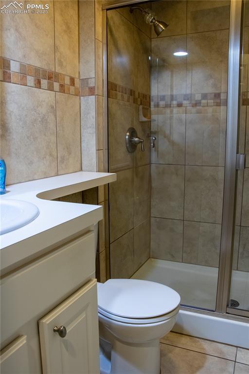 bathroom featuring a shower with door, vanity, tile patterned floors, and toilet