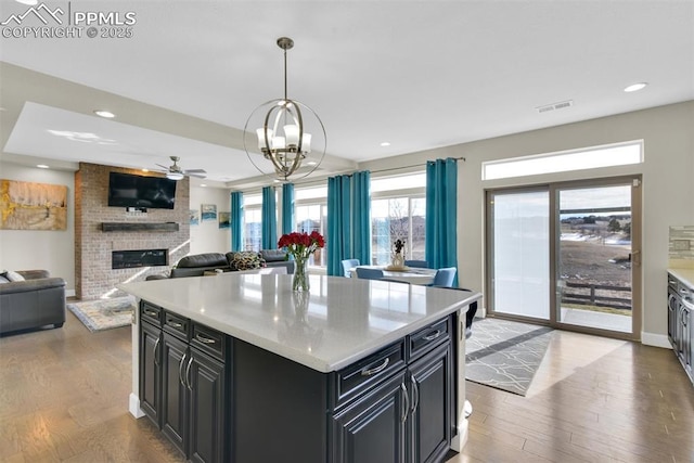 kitchen with visible vents, a fireplace, dark cabinetry, and wood finished floors