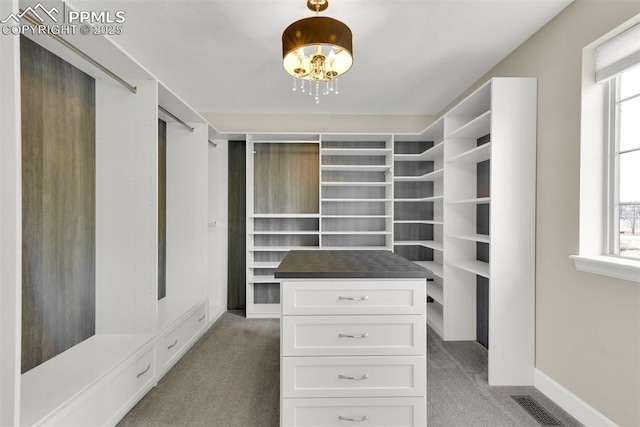 spacious closet featuring visible vents, light carpet, and a chandelier