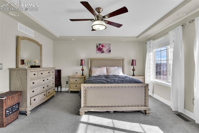 carpeted bedroom featuring visible vents, baseboards, and a tray ceiling