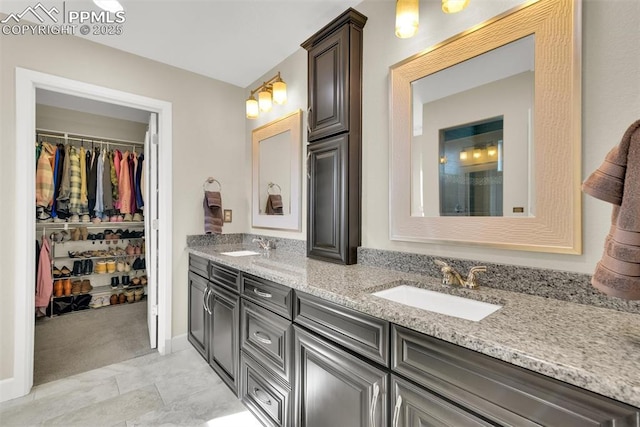 full bathroom featuring a walk in closet, double vanity, and a sink