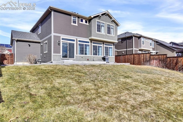 rear view of property featuring a yard and fence