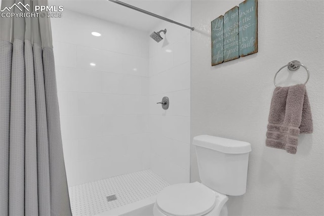 bathroom featuring toilet and a stall shower