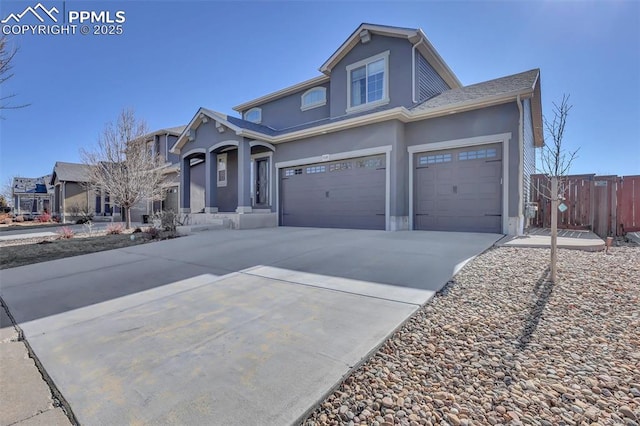 traditional-style house with stucco siding, driveway, a garage, and fence