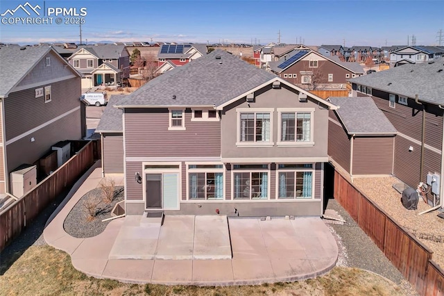 back of house featuring a residential view, roof with shingles, a fenced backyard, and a patio area