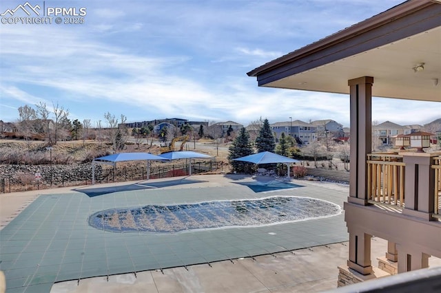 view of swimming pool with a patio, a swimming pool, fence, and a residential view