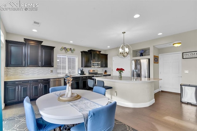 dining area with visible vents, wood finished floors, recessed lighting, an inviting chandelier, and baseboards