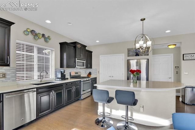 kitchen featuring a breakfast bar area, light countertops, light wood-style flooring, stainless steel appliances, and a sink