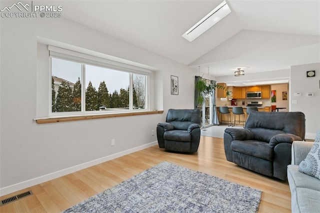 living room with vaulted ceiling with skylight, visible vents, light wood-style flooring, and baseboards