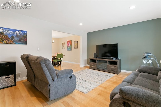 living room with light wood-style floors, visible vents, and baseboards