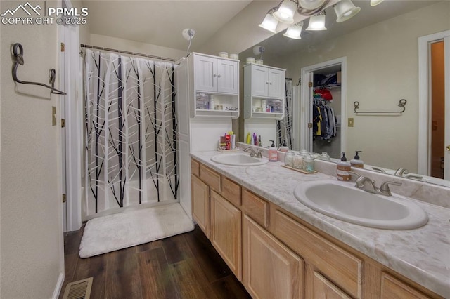 bathroom featuring double vanity, visible vents, a sink, and wood finished floors