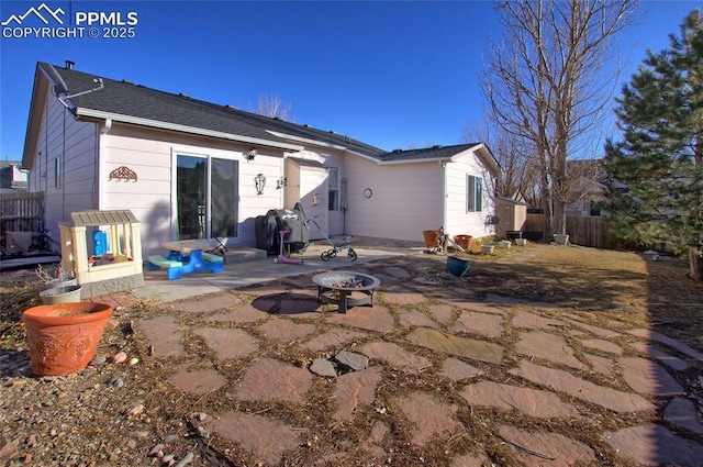 rear view of property featuring a fire pit, a patio area, and fence