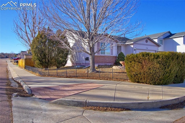 exterior space featuring a fenced front yard, brick siding, and a garage