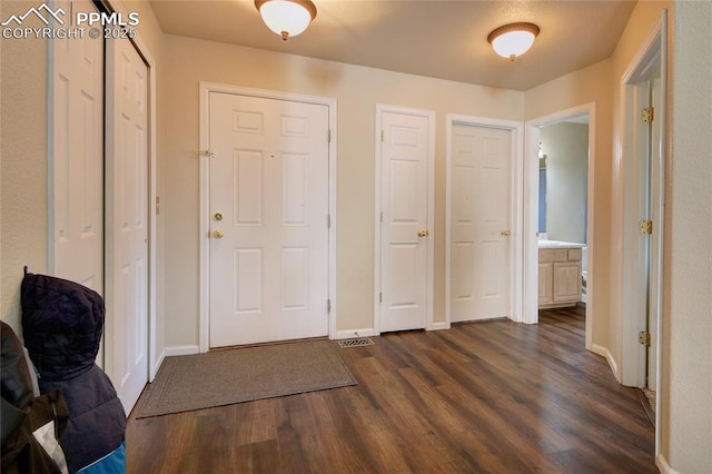 foyer entrance with dark wood-style floors and baseboards