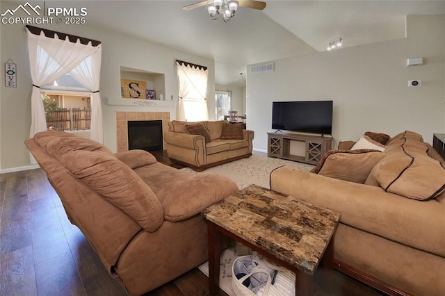 living area featuring a fireplace, wood-type flooring, visible vents, vaulted ceiling, and baseboards