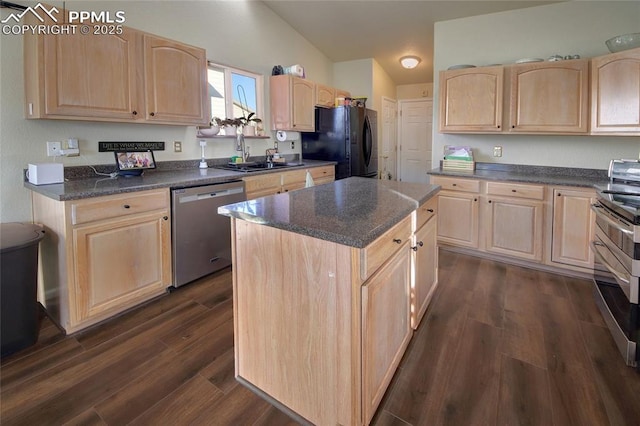 kitchen with dark countertops, appliances with stainless steel finishes, dark wood-type flooring, light brown cabinetry, and a sink