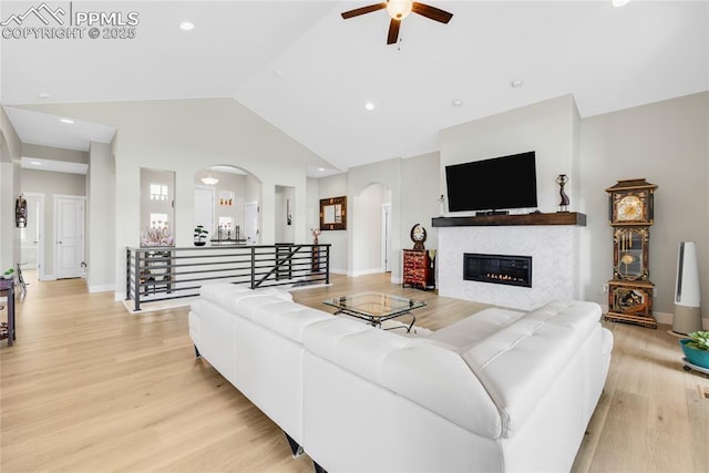 living room featuring ceiling fan, high vaulted ceiling, and light wood-type flooring