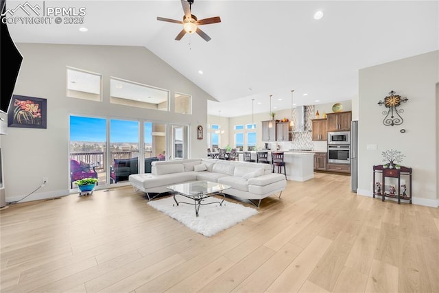 living room with ceiling fan, high vaulted ceiling, a healthy amount of sunlight, and light hardwood / wood-style floors