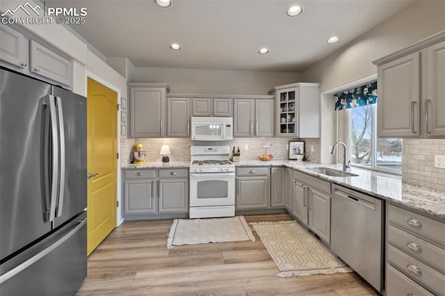 kitchen with gray cabinetry, sink, stainless steel appliances, and light hardwood / wood-style floors