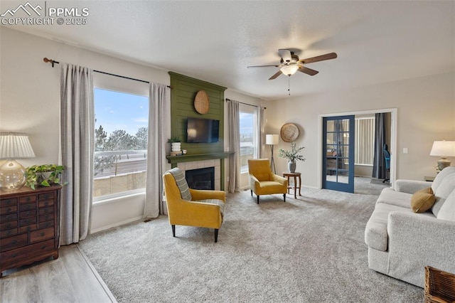 living room featuring french doors, ceiling fan, a tile fireplace, and light hardwood / wood-style flooring