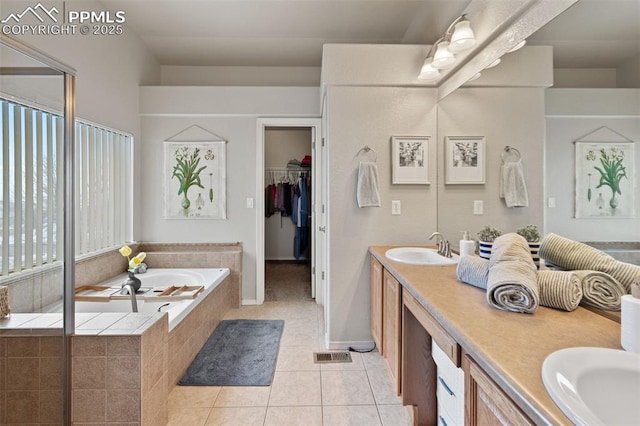 bathroom with vanity, tile patterned flooring, and tiled tub