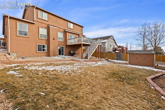 snow covered back of property with cooling unit, a storage shed, and a wooden deck